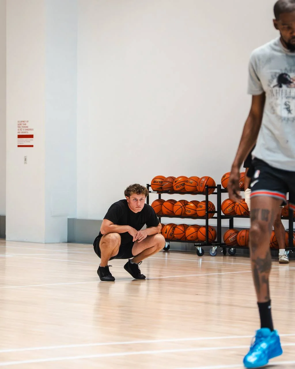 Justin Mucci crouched courtside, watching an NBA player train